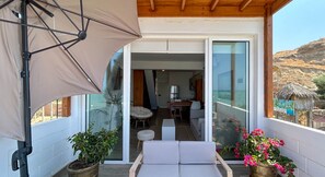 Relax on the balcony with a cushioned seating area, overlooking the dining space and the surrounding landscape.