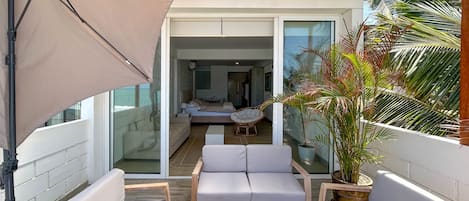 Un balcon avec un canapé, une chaise et une plante en pot.