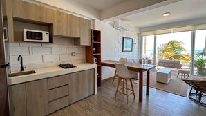 Une cuisine moderne dotée d’un four à micro-ondes encastré, de meubles en bois et d’un coin repas offrant une vue sur l’océan.