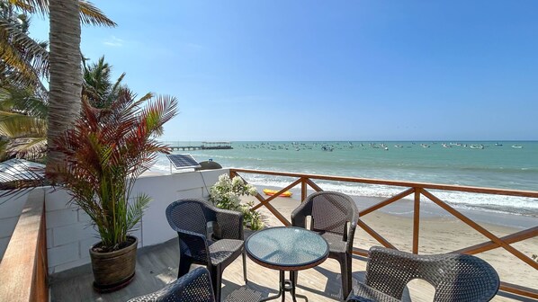 Relax on the seaside terrace with ocean views, a wicker chair, and a small table.