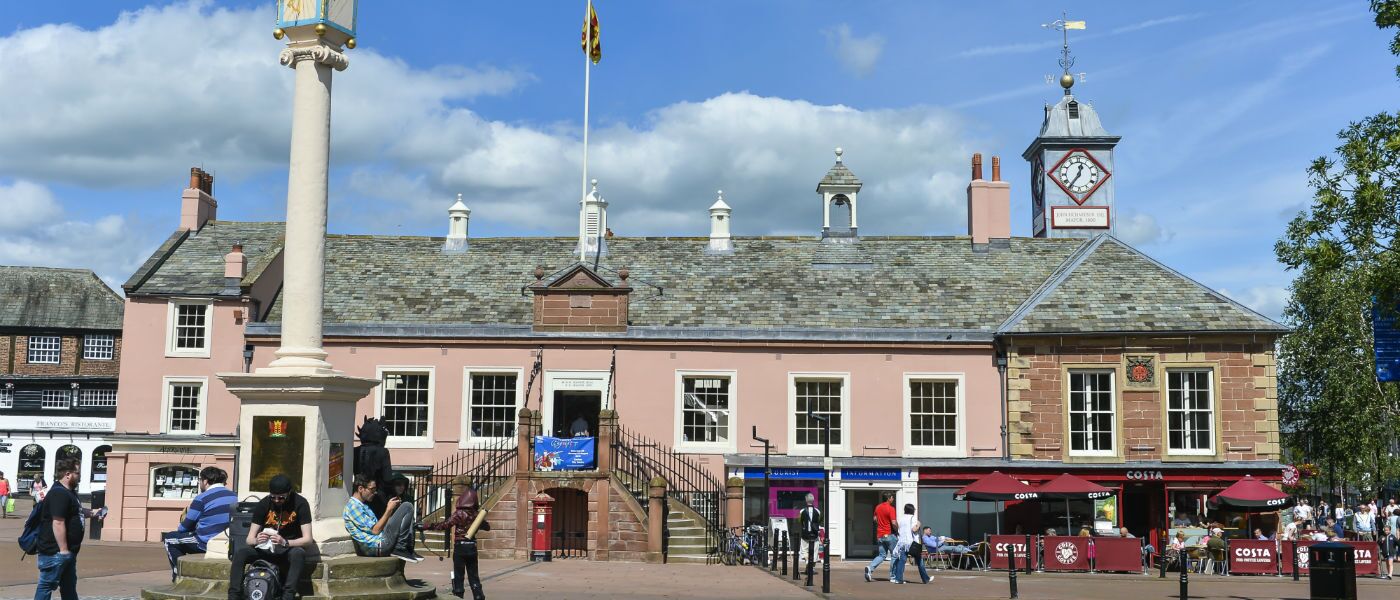 A historic building with a clock tower, a central staircase, and a flagpole.