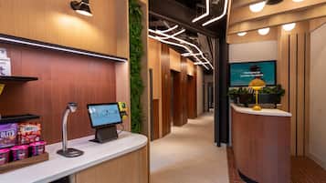 A modern reception area with a digital kiosk, a coffee machine, and a vending machine.