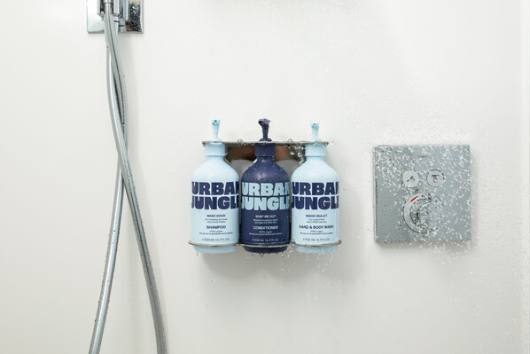 Une douche avec trois produits de la gamme Urban Jungle : un shampooing, un après-shampooing et un gel lavant pour les mains et le corps.