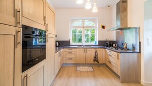 Eine moderne Küche mit Holzausstattung, Edelstahlgeräten und einem großen Fenster, das für natürliches Licht sorgt.