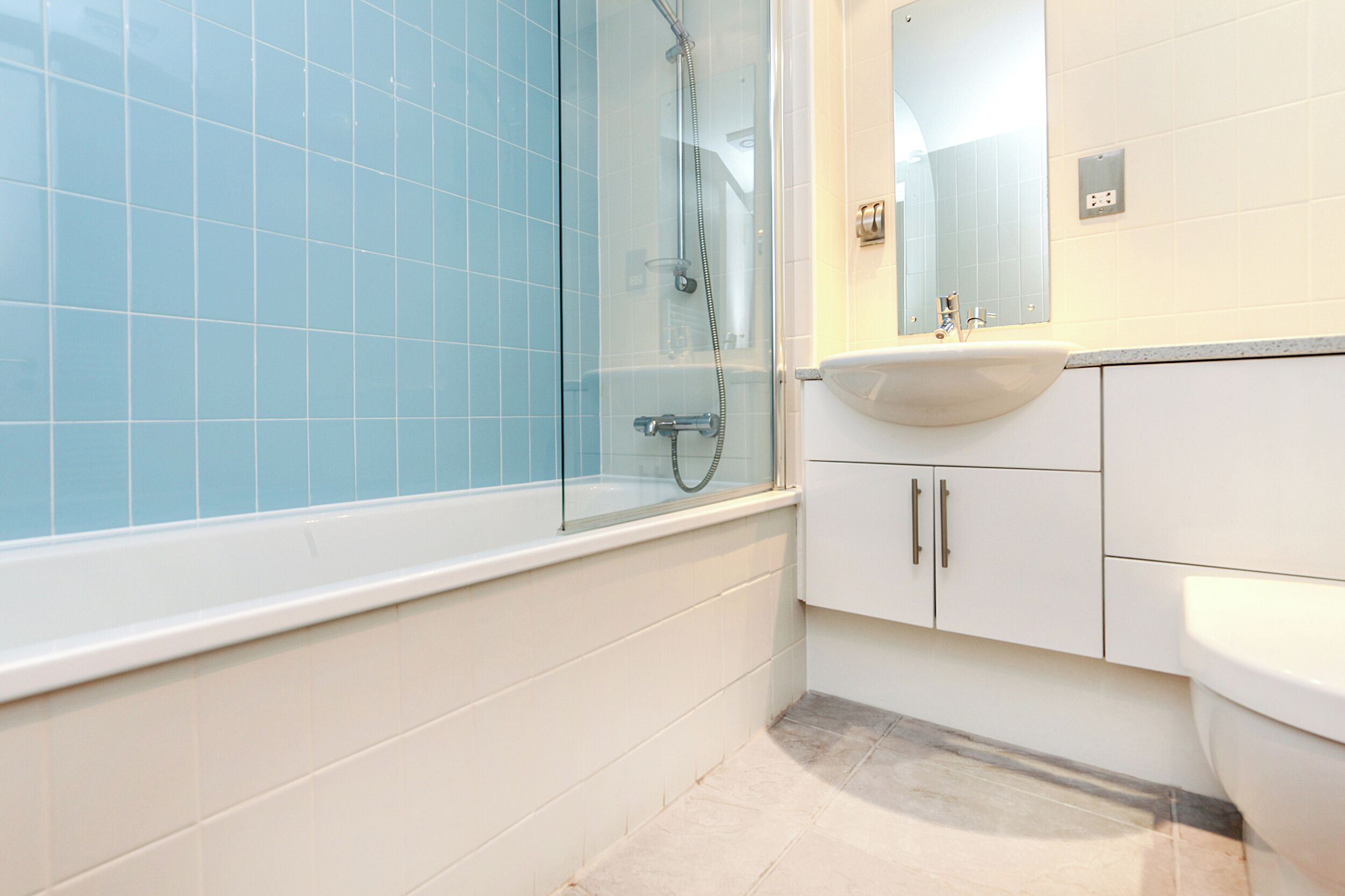 A bathroom with a glass-enclosed shower, a white sink, and a mirror above it.