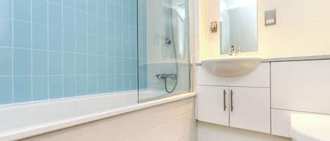 A bathroom with a glass-enclosed shower, a white sink, and a mirror above it.
