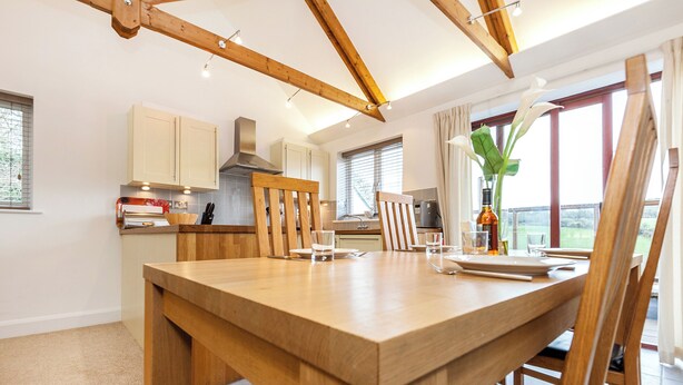 Una cocina moderna con vigas de madera, una mesa de comedor y vistas al exterior.