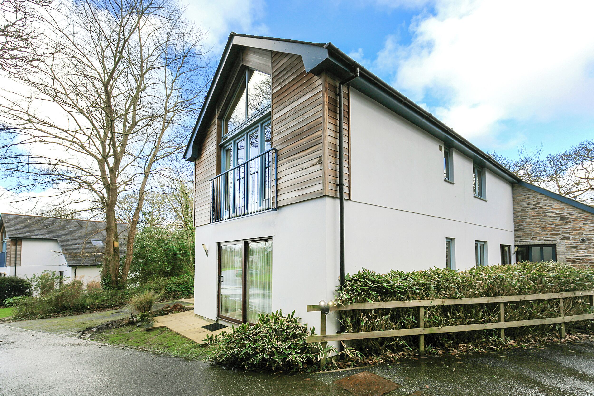 A modern two-story house with a sloped roof, large windows, and a stone facade.