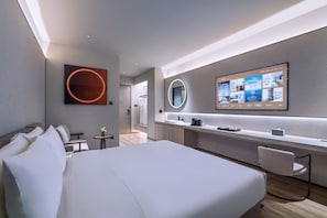 Une chambre d’hôtel moderne, dotée d’un grand lit, d’un bureau et d’un téléviseur affichant les équipements disponibles dans la chambre.