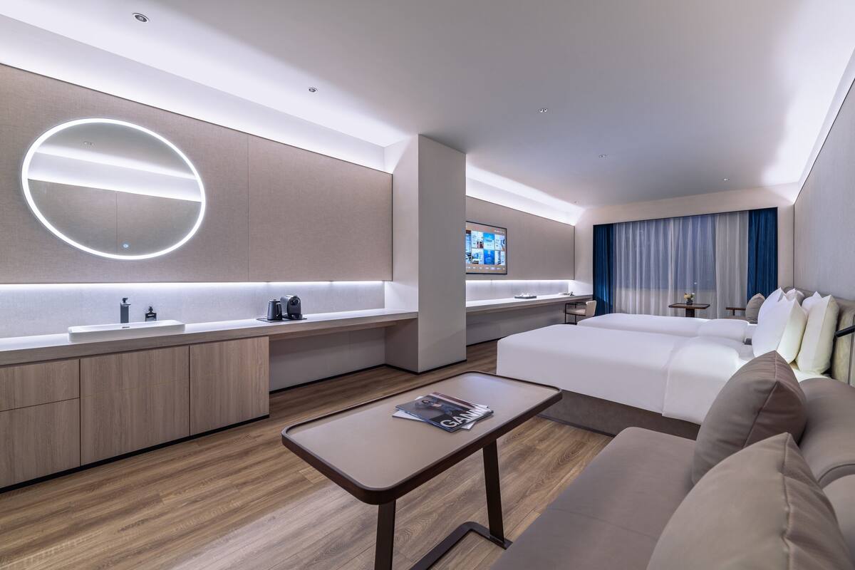 Une chambre d’hôtel moderne dotée d’un îlot central, d’un téléviseur à écran plat, d’un canapé et d’une table basse.