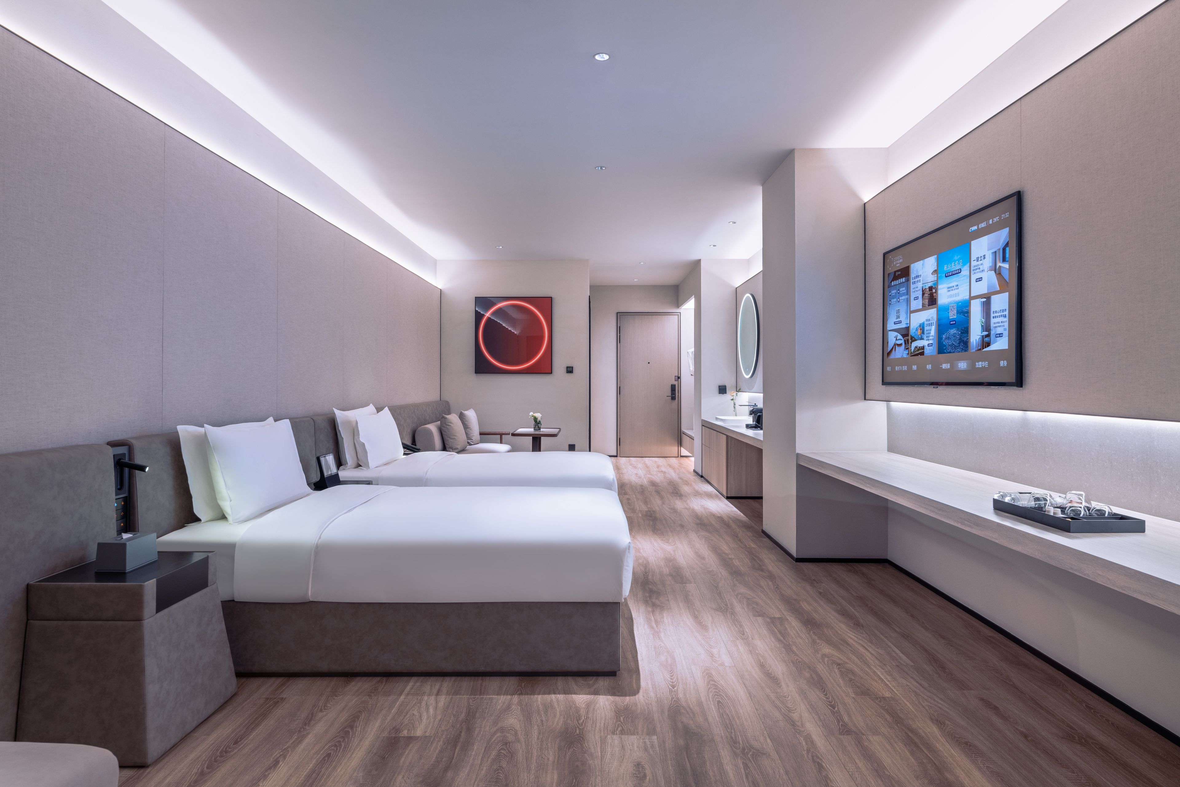 A modern hotel room with a large bed, bedside tables, a small table, and a wall-mounted TV.