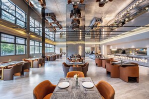 Un restaurant moderne avec de hauts plafonds, de grandes fenêtres et un bar central.