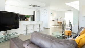 Una sala de estar moderna con un televisor de pantalla plana grande, una mesa de centro de vidrio y un sofá de cuero.