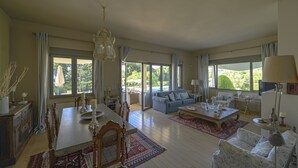 Ein geräumiges Wohnzimmer mit Essbereich, großen Fenstern und Blick ins Freie.