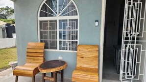 Um pátio com duas cadeiras de madeira e uma mesa redonda pequena.