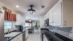 Una cocina con armarios blancos, encimeras negras y salpicadero de azulejos.