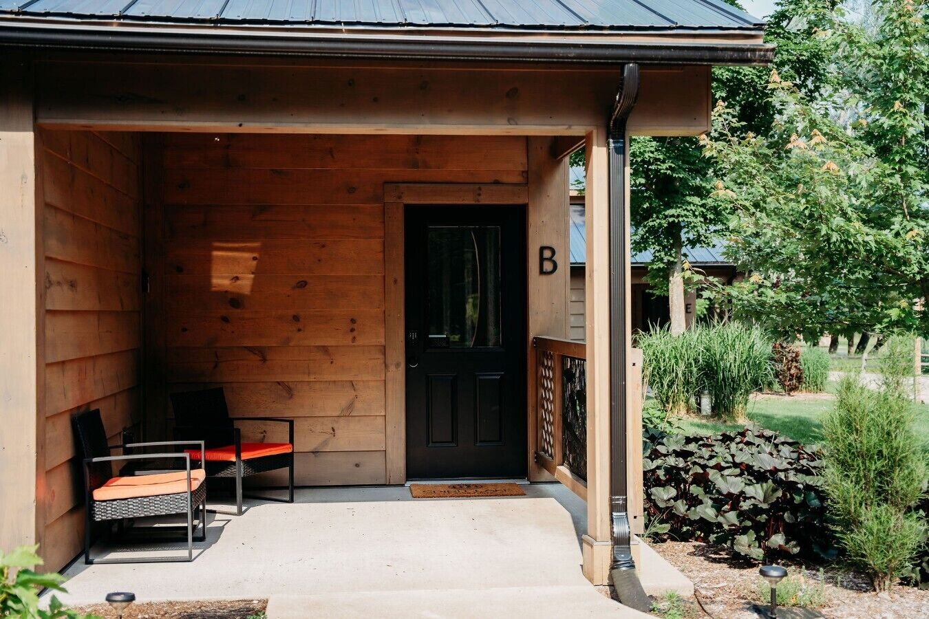 A wooden building with a black door marked with a 'B'.
