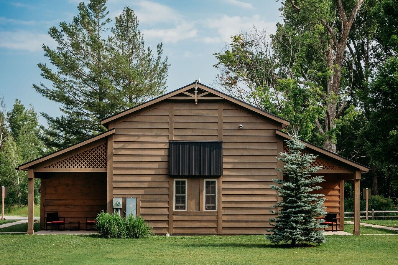Une cabane en bois avec un porche couvert, une petite fenêtre et une cheminée.
