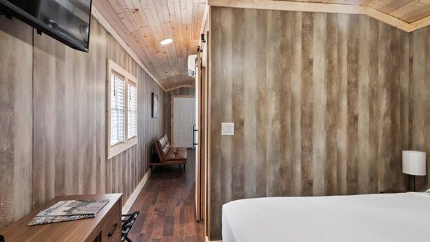 Un intérieur en bois comprenant un lit, un bureau et un téléviseur.