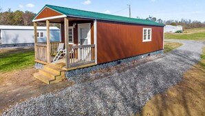 Une petite cabane en bois d’un seul étage, dotée d’un porche et d’un toit végétalisé, entourée de gravier et d’herbe.