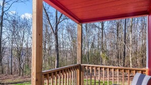 A wooden deck with a red roof, surrounded by trees. - Tiny cabin on 10 acres with pond (Albertville)