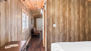 A narrow hallway with wooden walls and a bench. There is a door at the end of the hallway. - Tiny cabin on 10 acres with pond (Albertville)