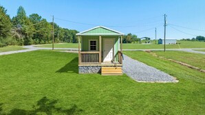 Een klein, gelijkvloers huis met een groene gevel en een houten veranda.