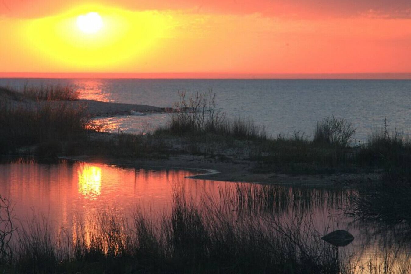 A sunset over a body of water with reflections on the surface.