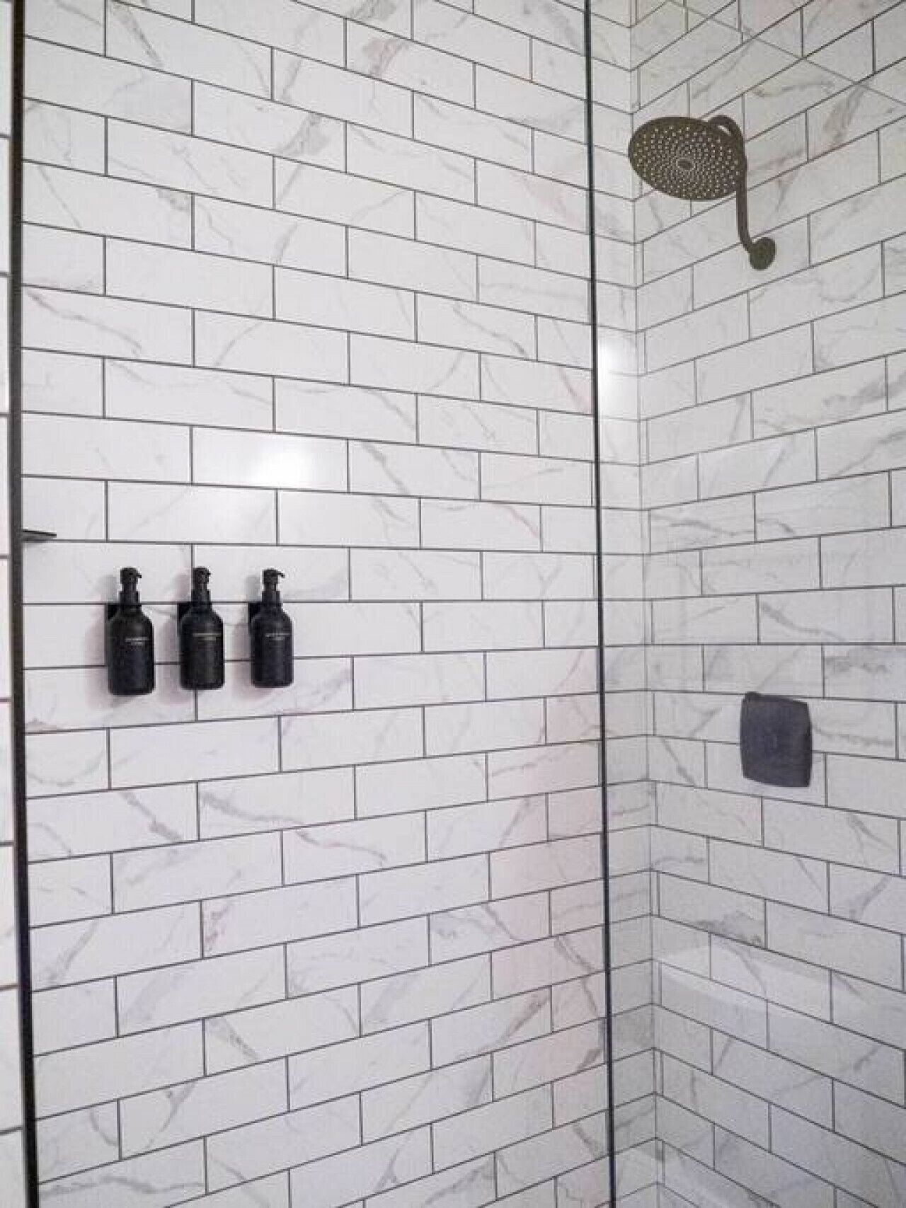 Een douche met witte marmeren tegels en een handdouche.