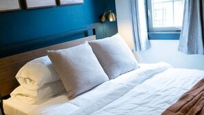 Ein Hotelzimmer mit einem großen Bett, einem Kopfteil und einem Fenster mit Vorhängen.