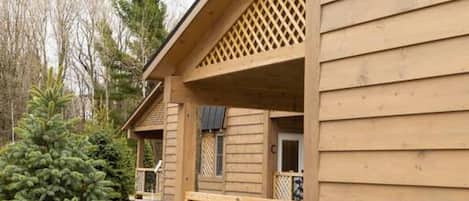 A wooden cabin with a balcony, number 2, surrounded by trees.