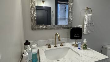 A bathroom with a white marble sink, a large mirror with a decorative frame, and a vanity with drawers.