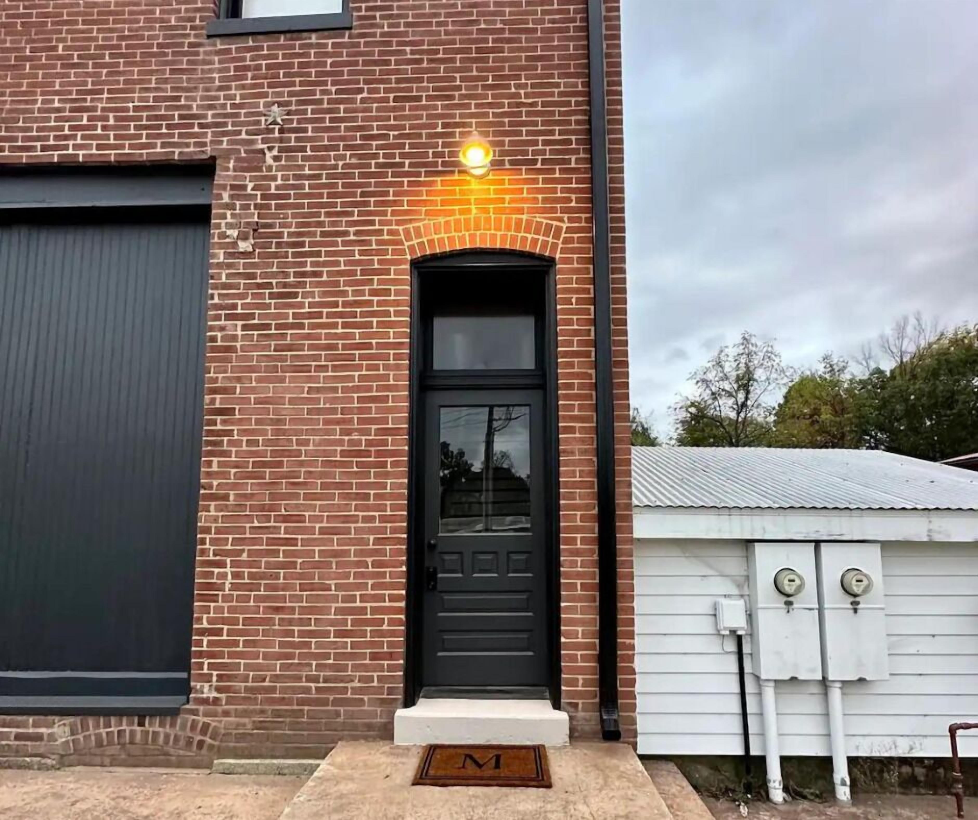 A brick building with a black door and a small porch.