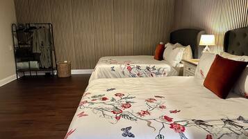 A hotel room with two beds, a wardrobe, a nightstand, and a lamp.