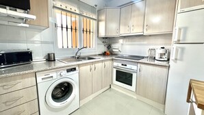 Une cuisine moderne équipée d’un lave-linge, d’une machine à café et d’un réfrigérateur.