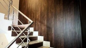 A staircase with a metal railing leading to a landing, a dark wooden wall, and a red carpet. - A room facing the holy Ganges (Muni Ki Reti, Rishikesh)
