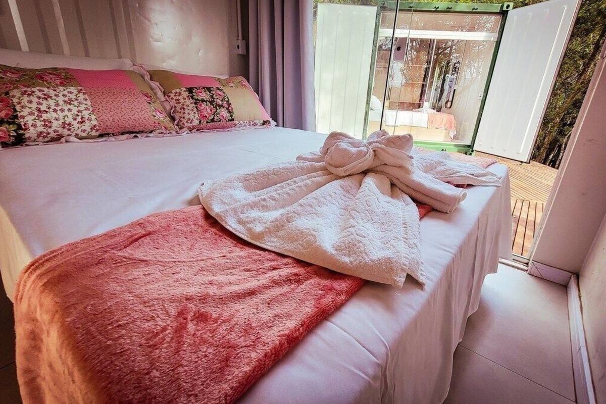 A bedroom with a bed, a pink blanket, and a white towel.