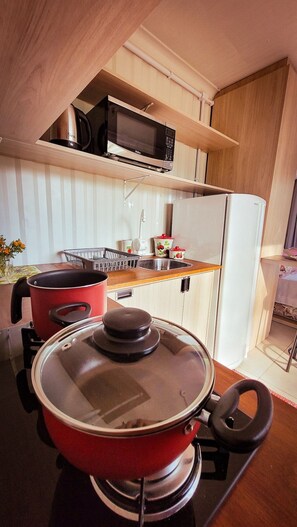 Een koelkast, een kookplaat, kookgerei, borden en bestek