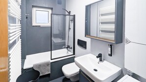 Ein modernes Badezimmer mit einer Duschkabine, einem weißen Waschbecken und einer Toilette.