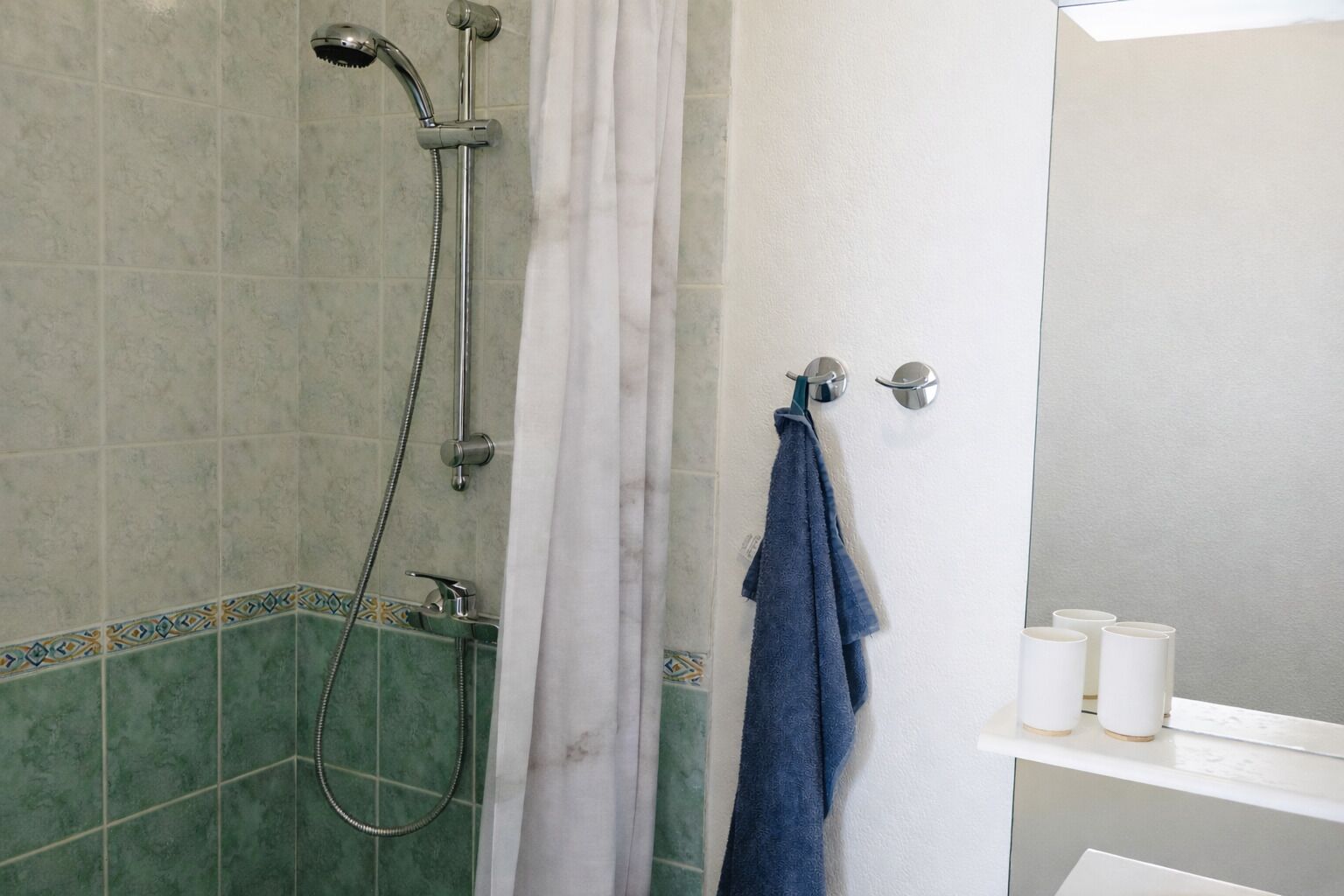 Ein Badezimmer mit Dusche, Handtuchhalter und Ablage für Toilettenartikel.