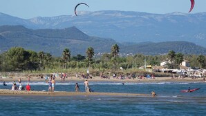 Une plage avec des gens, des tentes et un bateau rouge.