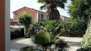 Une maison avec un jardin, un palmier et une clôture.