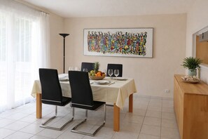 A dining area with a table set for two, chairs, a fruit bowl, and a painting on the wall. - Quiet holiday home with pool, A/C & private terrace for 4 guests (Saint Aygulf)