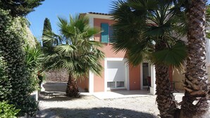 Un bâtiment à la façade beige, avec une porte de garage blanche et un petit porche.