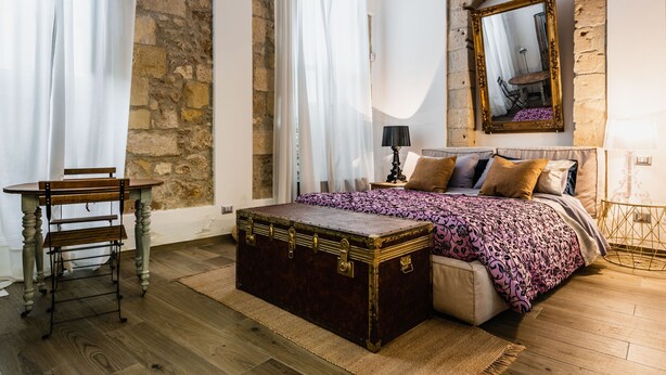 A bedroom with a wooden bed, a large mirror, a chest of drawers, and a desk with a chair. - Dolce Suite Near Syracuse Cathedral by Wonderful Italy (Syracuse)