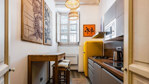A compact kitchen with a wooden table, a yellow refrigerator, and a microwave. - Dolce Suite Near Syracuse Cathedral by Wonderful Italy (Syracuse)
