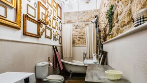 A compact bathroom with a white toilet, a white sink, a bathtub, and a wooden vanity. - Dolce Suite Near Syracuse Cathedral by Wonderful Italy (Syracuse)