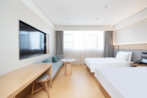 Habitación de hotel con cama, escritorio, televisor, sofá y una mesita.