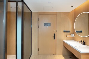 Een moderne badkamer met een houten wastafelmeubel, een spiegel en een douchecabine met glazen wanden.