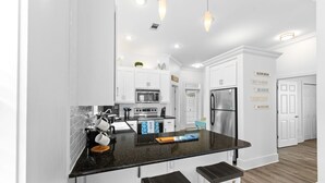 A modern kitchen with white cabinets, a black countertop, stainless steel appliances, and pendant lighting. - 30A Cottage, Walk to Beach, 2 Pools, Bikes&Chairs (Santa Rosa Beach)